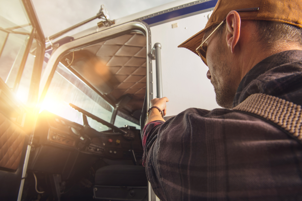 image of a semi truck driver climbing into the cab of a truck after being hired by a CDL driver staffing agency in Inland Empire