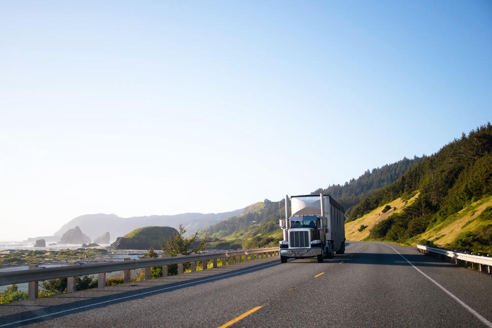 image of semi truck traveling down the beach front road