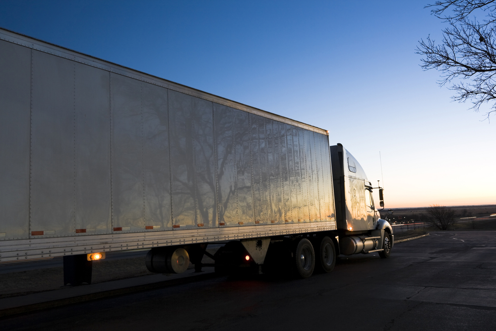 White semi truck after sunset being driven by a driver hired by a CDL staffing agency in san leandro